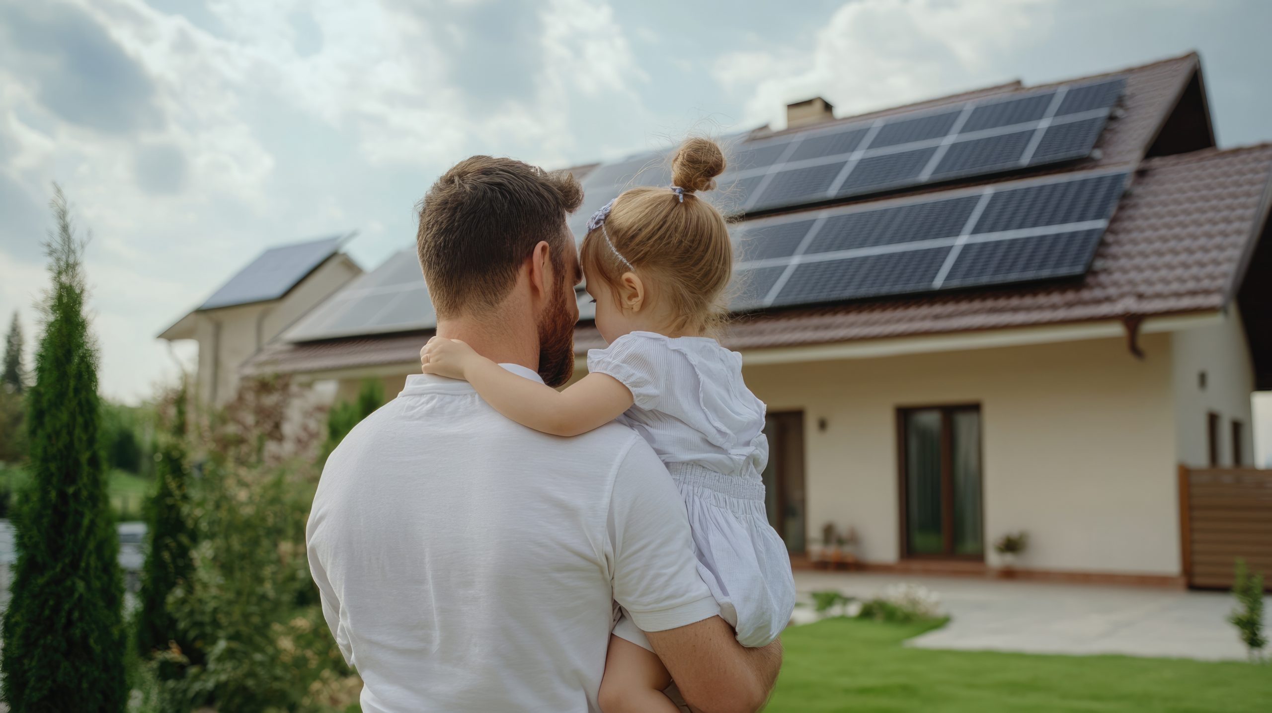 Família em frente a uma casa com painéis solares